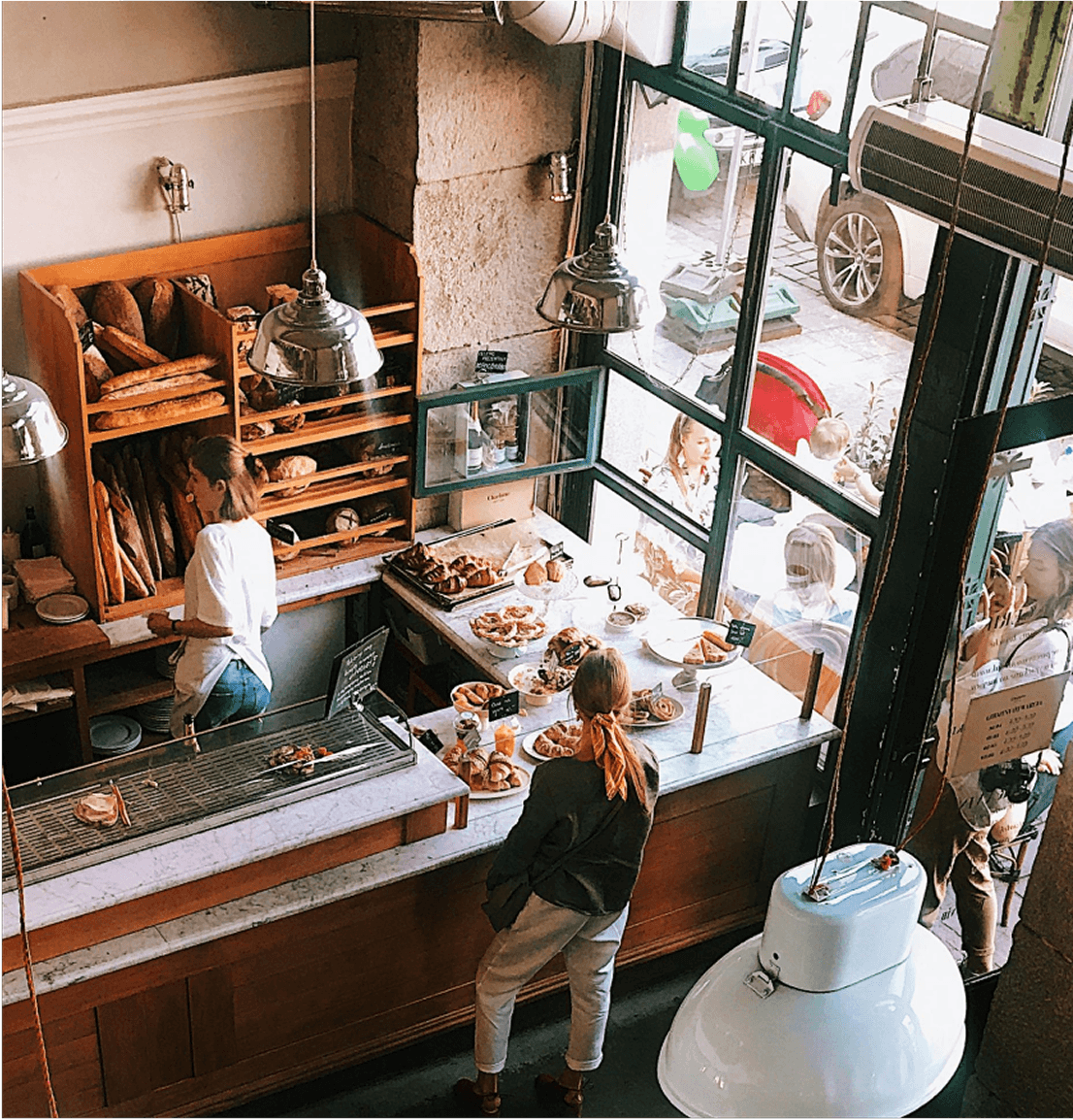 Customer browsing pastries at a local British Columbia bakery while staff prepares fresh bread